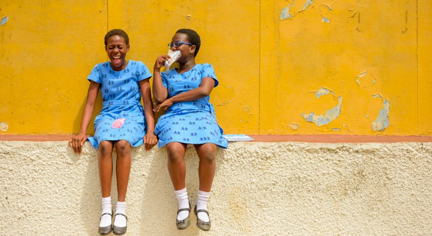 Ghana kinderdorp Tema twee vriendinnen lachend bij hun school